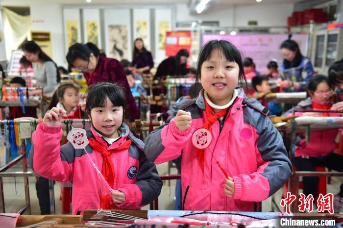 圖為小學(xué)生展示繡制好的2022年北京冬奧會吉祥物“冰墩墩”形象。　喻云亮 攝