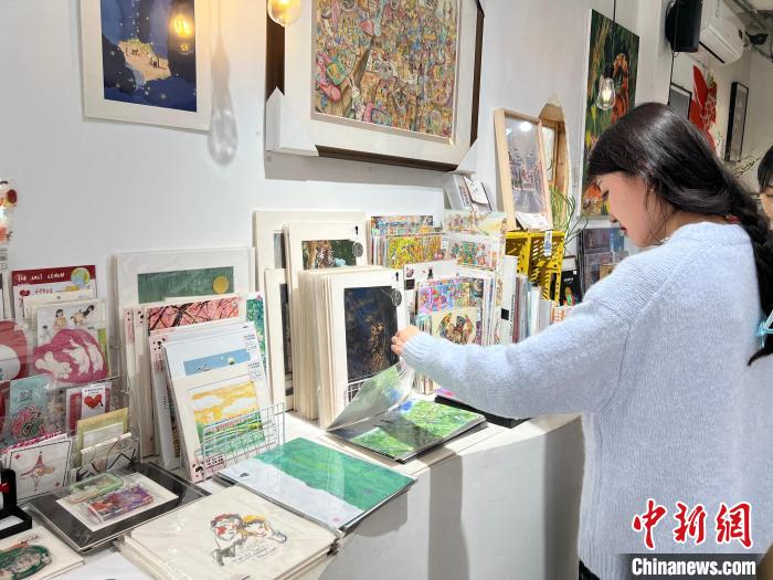 圖為藝術(shù)品商店內(nèi)，顧客挑選插畫作品?！＄婌?攝