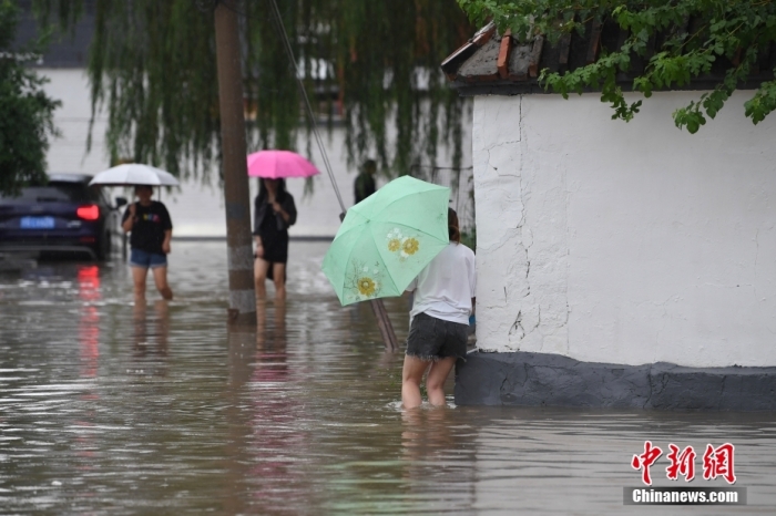 7月31日，市民行走在雨中的北京房山區(qū)瓦窯頭村。北京市氣象臺當日10時發(fā)布分區(qū)域暴雨紅色預警信號。北京市水文總站發(fā)布洪水紅色預警，預計當日12時至14時，房山區(qū)大石河流域將出現紅色預警標準洪水。<a target='_blank' href='/'><p  align=