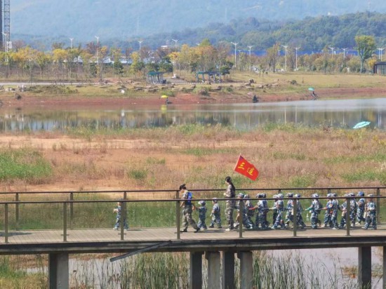 　　10月24日，秋游的幼兒園小朋友在老師帶領下走在清水塘公園里的木橋上。本報記者 常雯宜攝