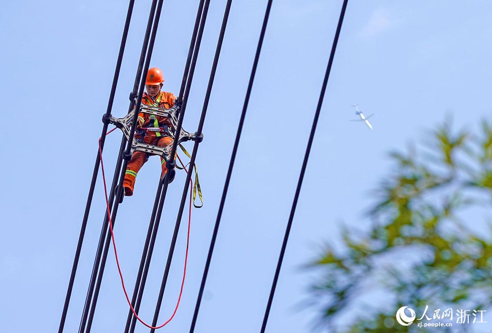 3月11日，在浙江省諸暨市河上鎮(zhèn)，浙江省送變電工程有限公司檢修人員在高空的導線上進行線路檢修維護。人民網(wǎng) 章勇濤攝