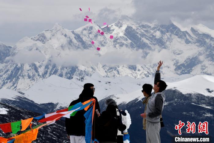 圖為5月14日，游客在西藏林芝色季拉山觀景臺(tái)拋灑“隆達(dá)”(風(fēng)馬旗，藏族民眾的一種祈福方式)。　李林 攝