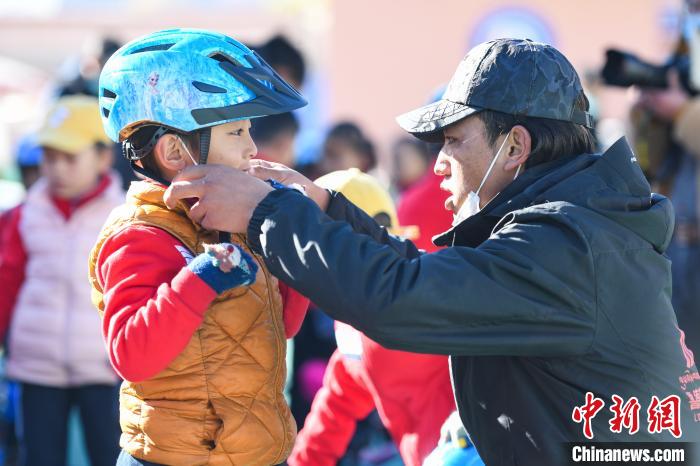 圖為拉薩市實(shí)驗(yàn)幼兒園孩子在教練的幫助下穿戴頭盔?！『闻罾?攝