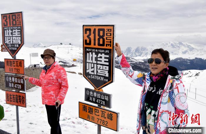 圖為5月14日，西藏林芝色季拉山觀(guān)景臺(tái)，游客與南迦巴瓦峰合影。　李林 攝